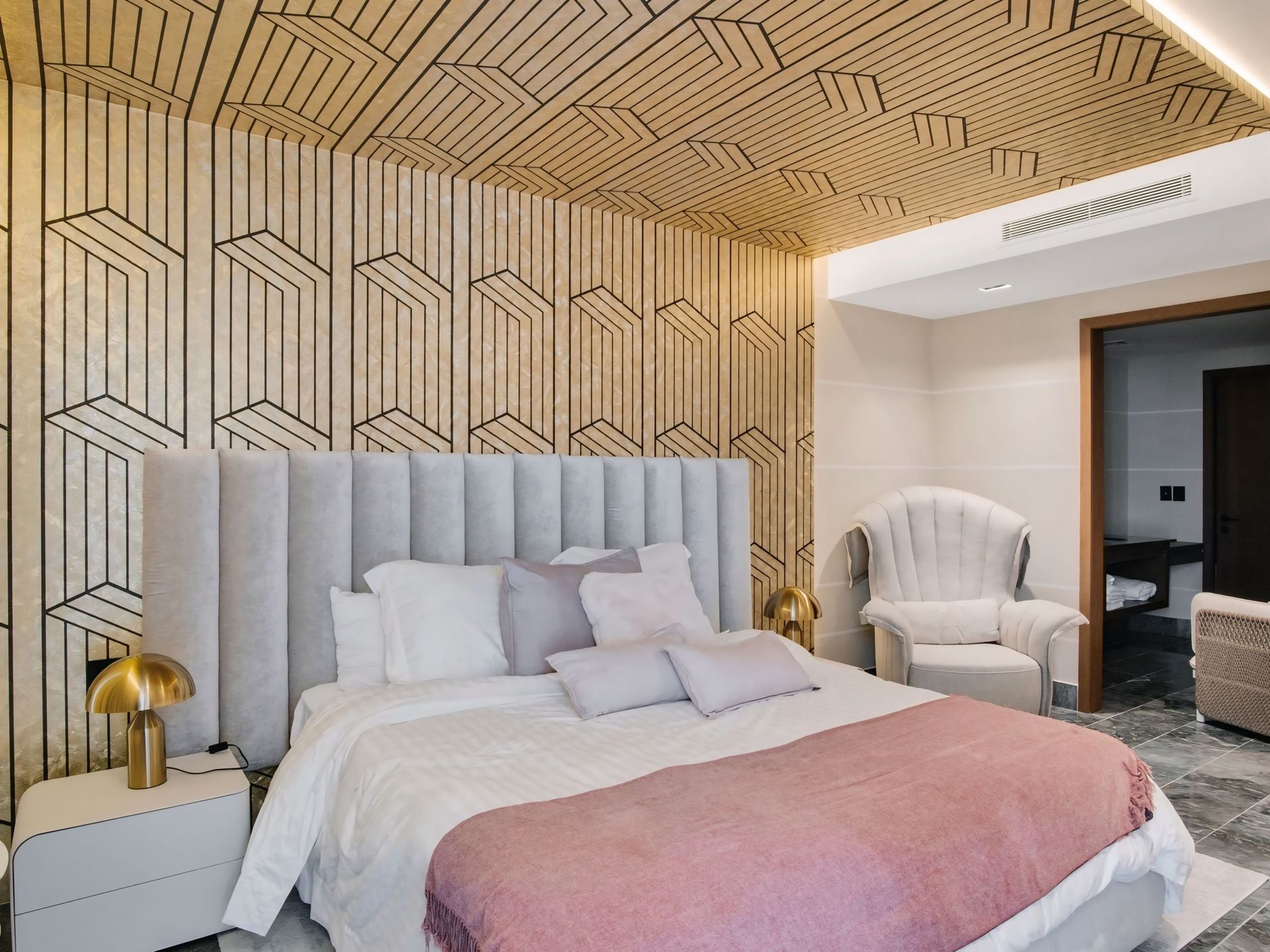 Een slaapkamer met een groot bed en een stoel.