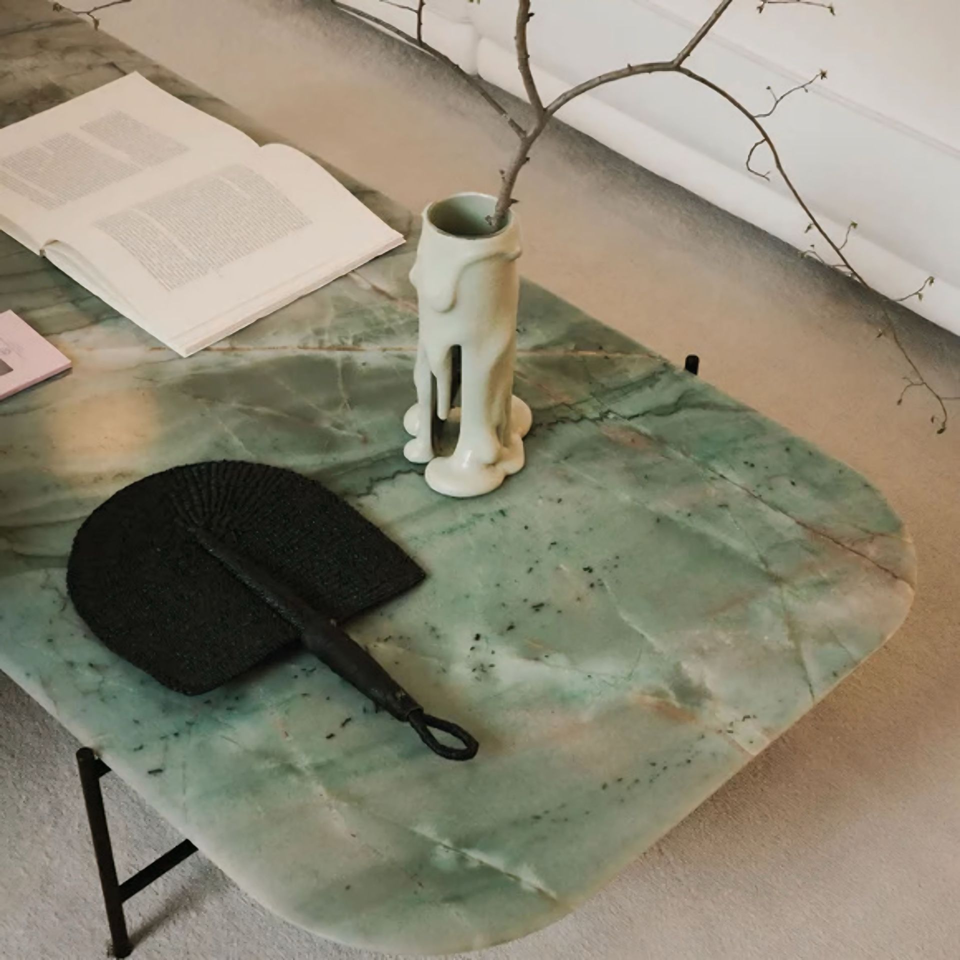 Een tafel met een vaas en een waaier erop