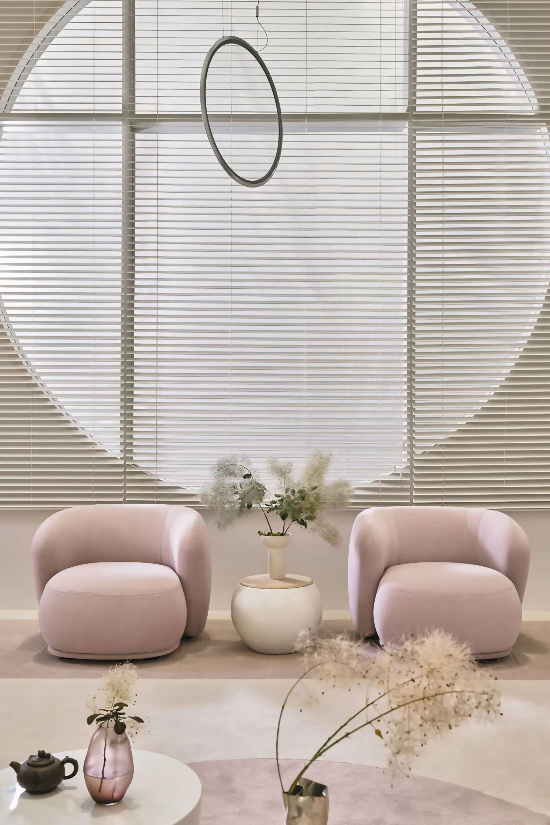 Een woonkamer met twee roze stoelen en een vaas met bloemen.