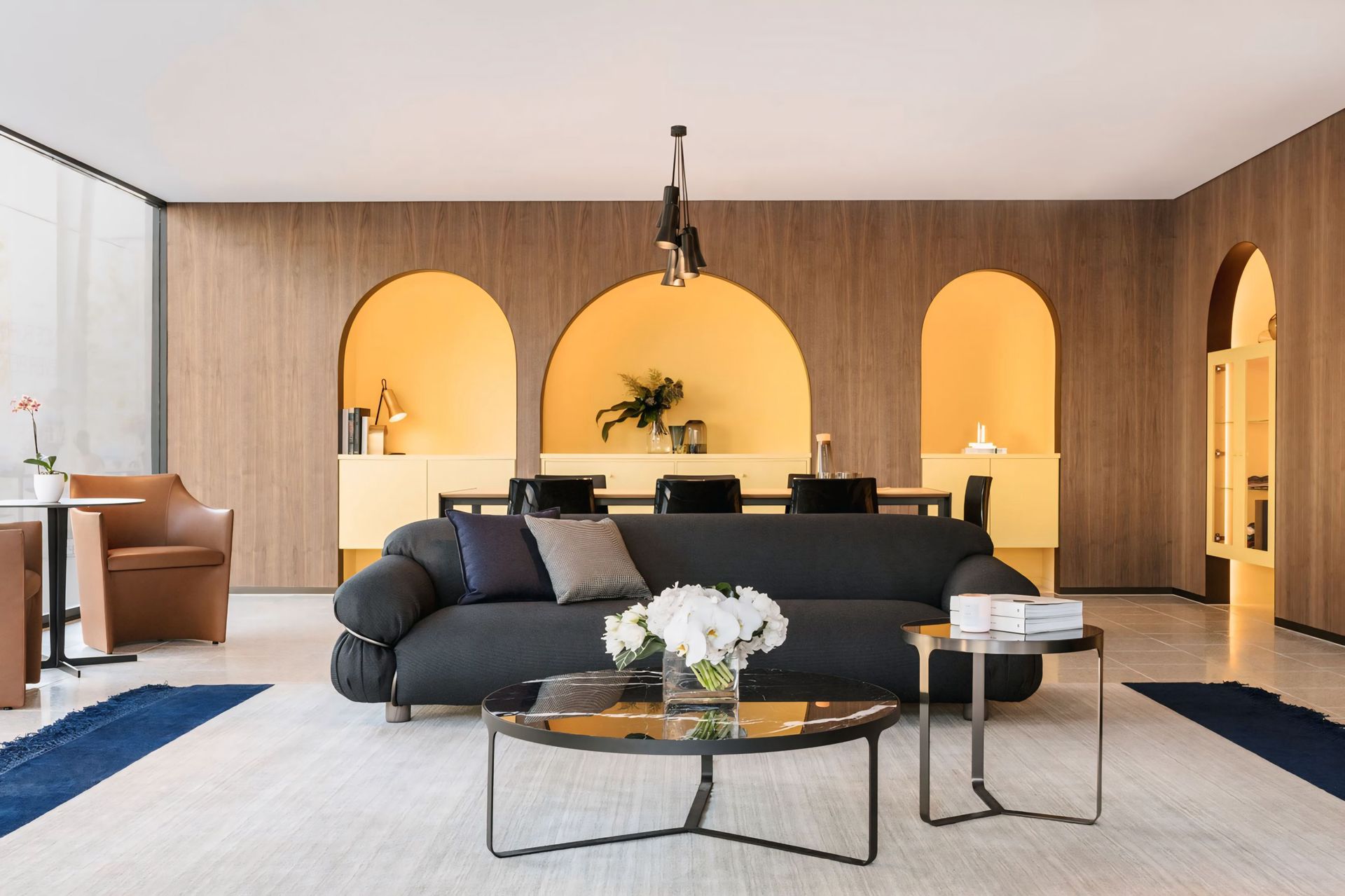 Een woonkamer met een zwarte bank en twee salontafels.