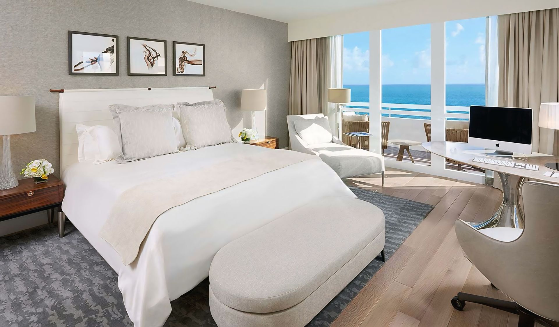 Een slaapkamer met een groot bed en een bureau met uitzicht op de oceaan.