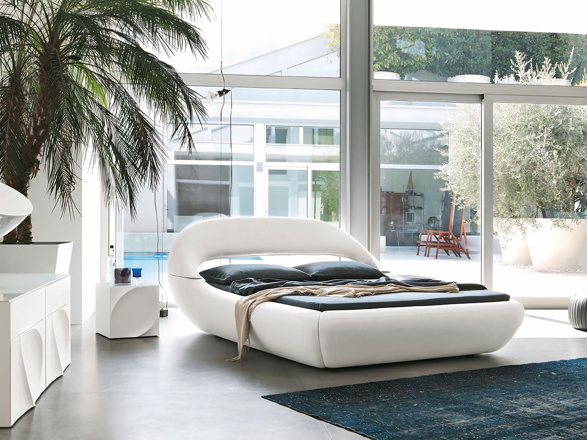 Een slaapkamer met een wit bed en een groot raam