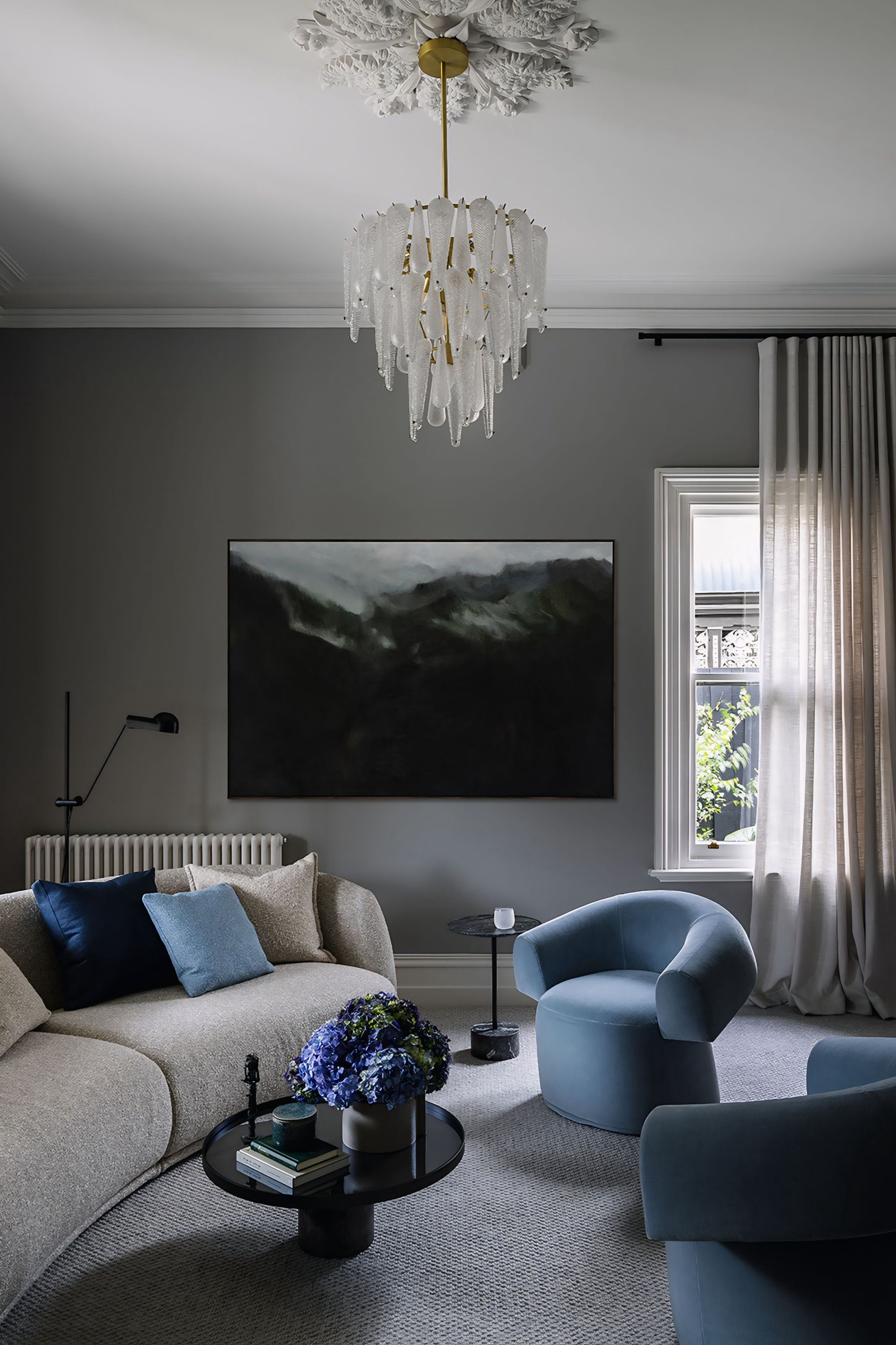 Een woonkamer met een bank, stoelen, een tafel en een kroonluchter.