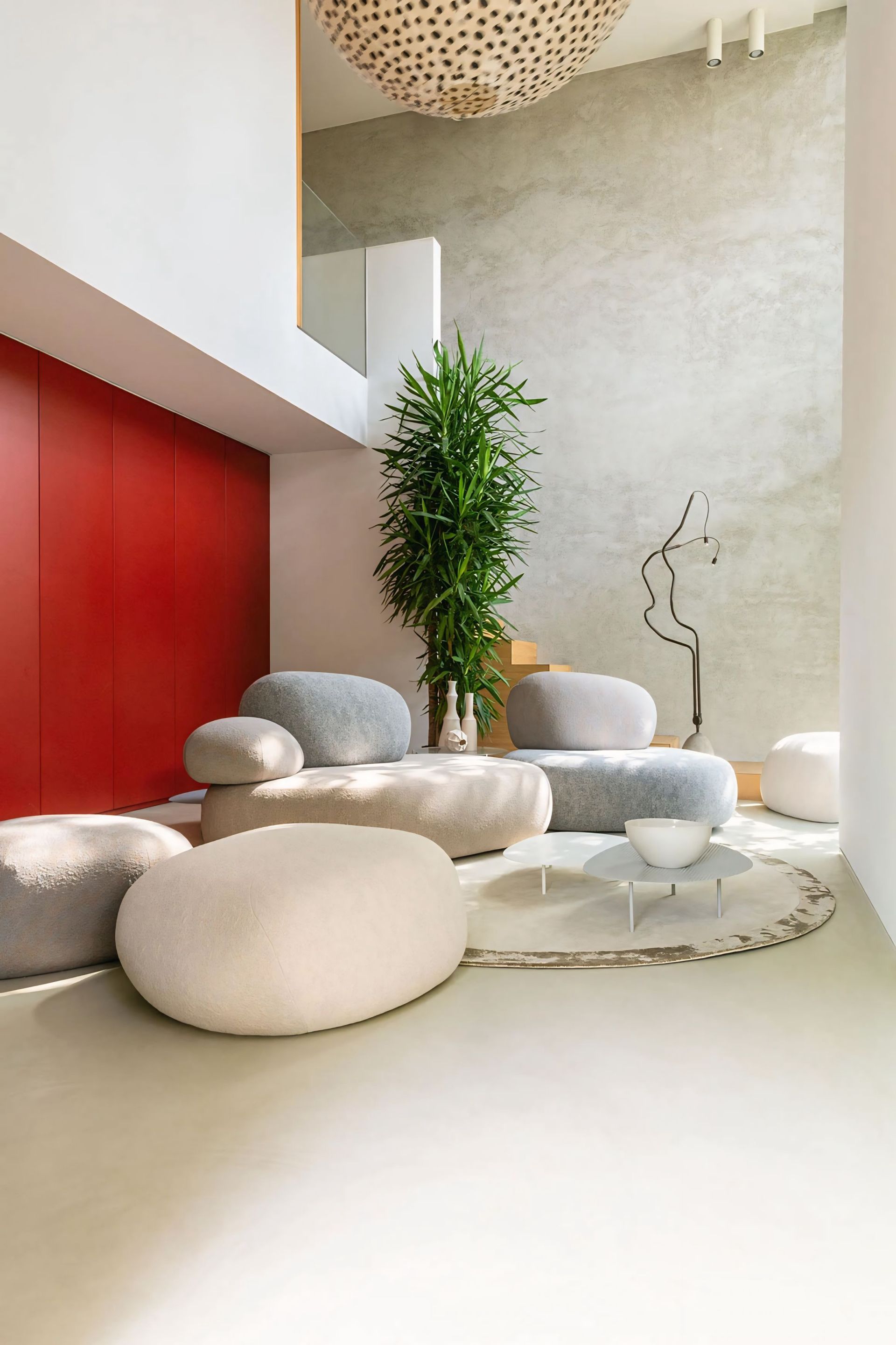 Een woonkamer met een bank, stoelen, voetenbankjes en een plant.