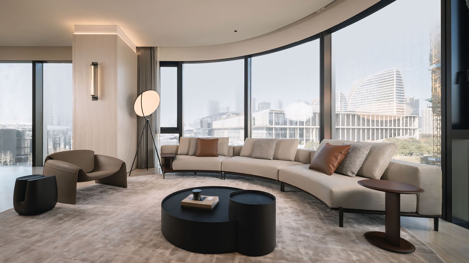 Een woonkamer met een gebogen bank, stoelen en een salontafel.