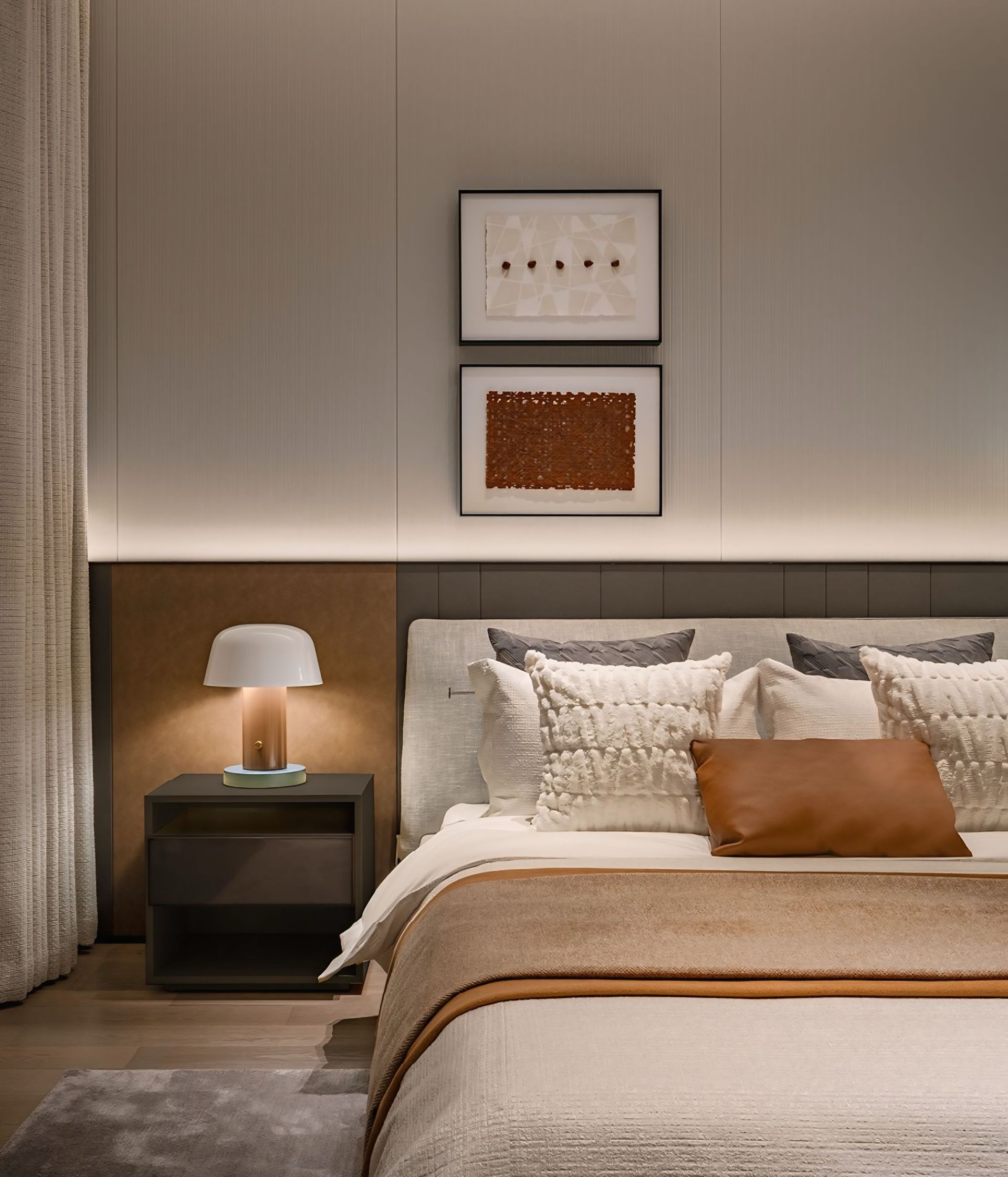 Een slaapkamer met een bed, nachtkastje, lamp en schilderijen aan de muur.