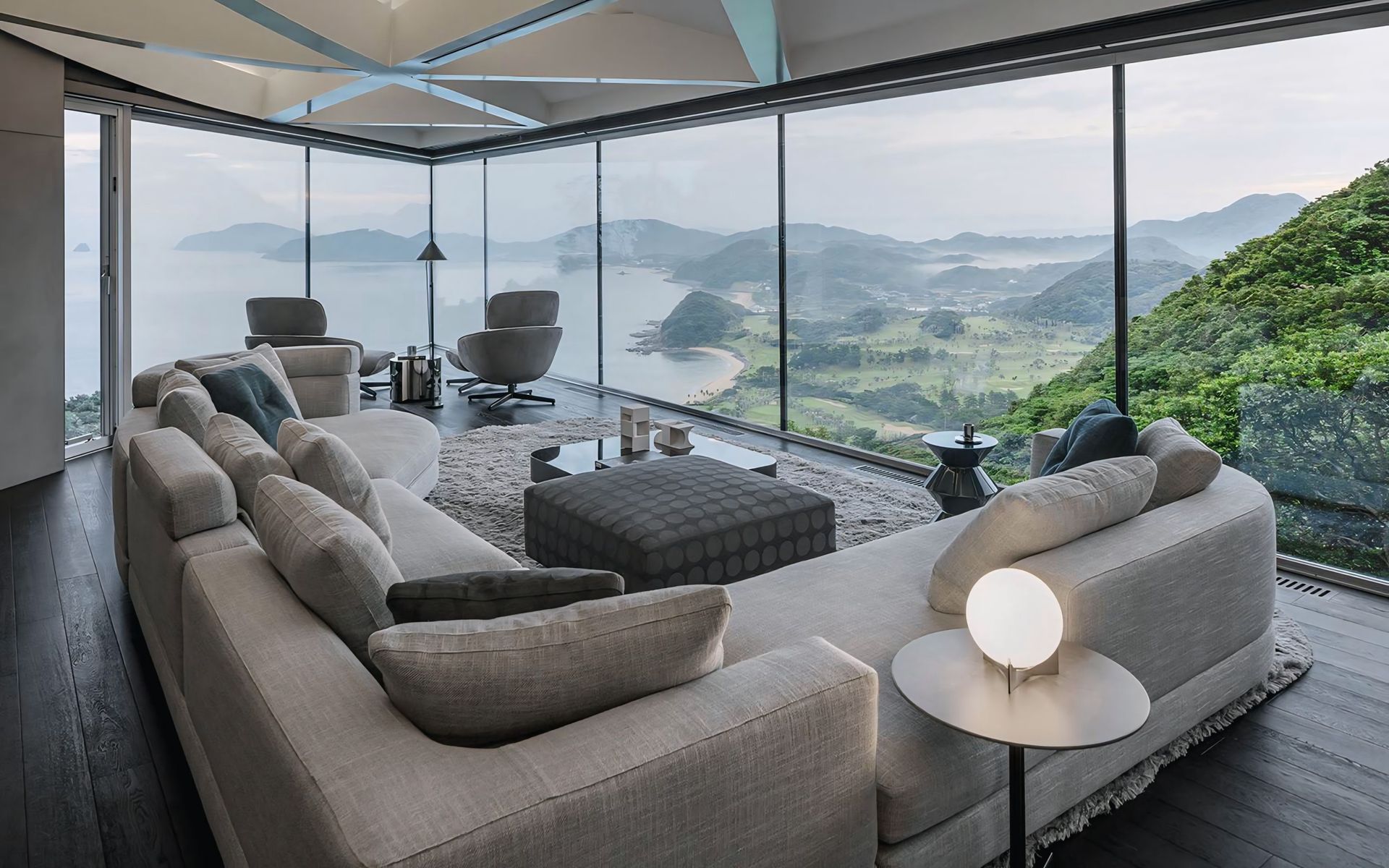 Een woonkamer met een bank, stoelen en uitzicht op de oceaan.