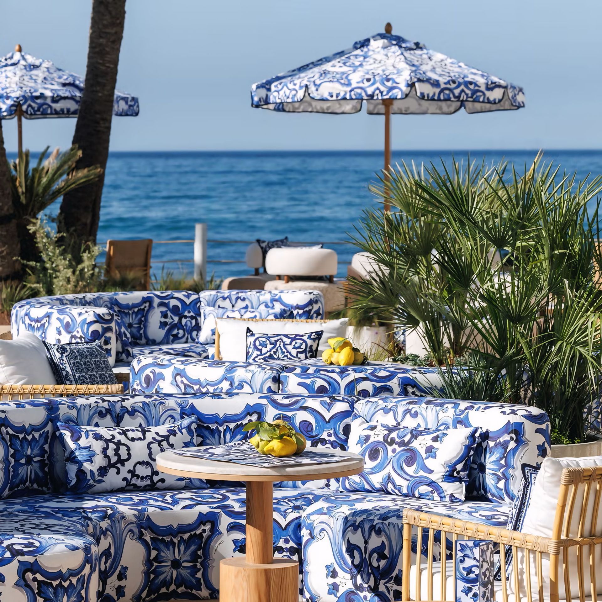 Een terras met blauw en wit meubilair en parasols met uitzicht op de oceaan