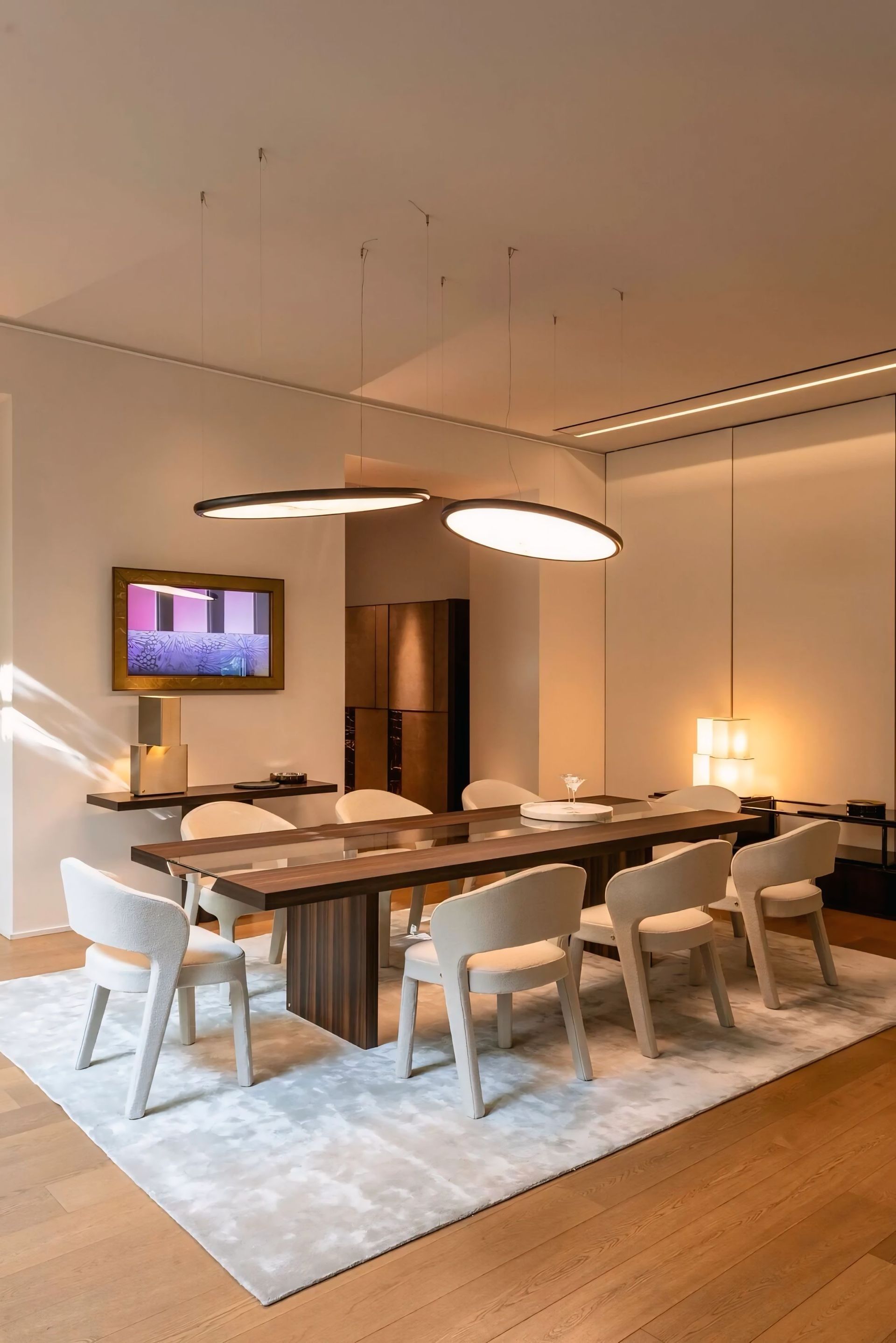 Een eetkamer met een lange tafel, stoelen en een kleed.