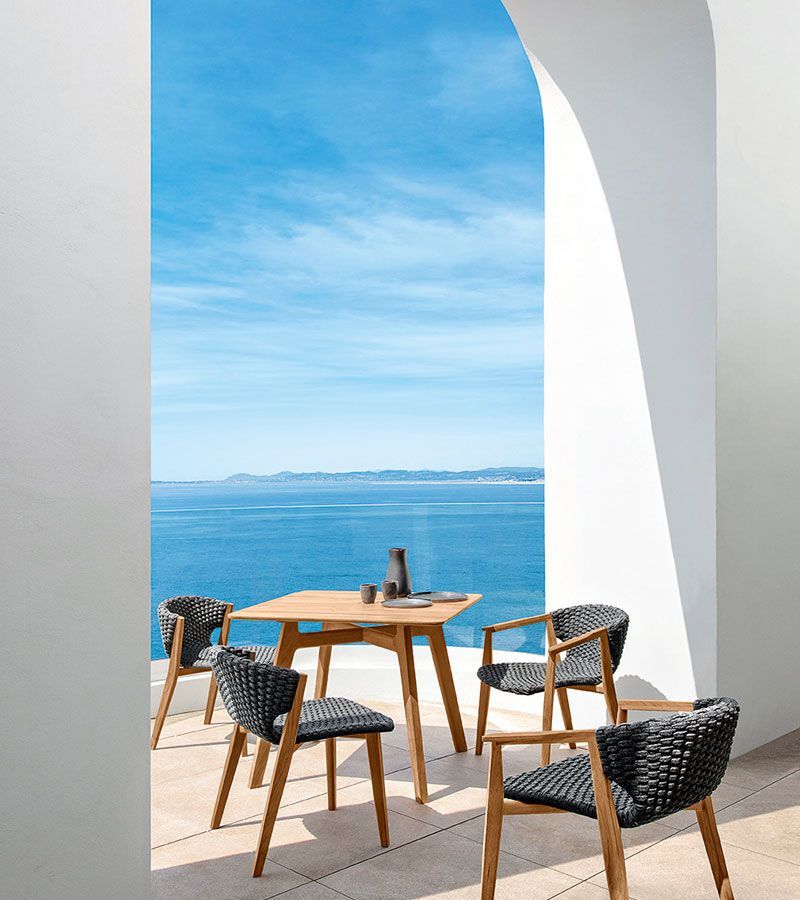 Een tafel en stoelen op een balkon met uitzicht op de oceaan