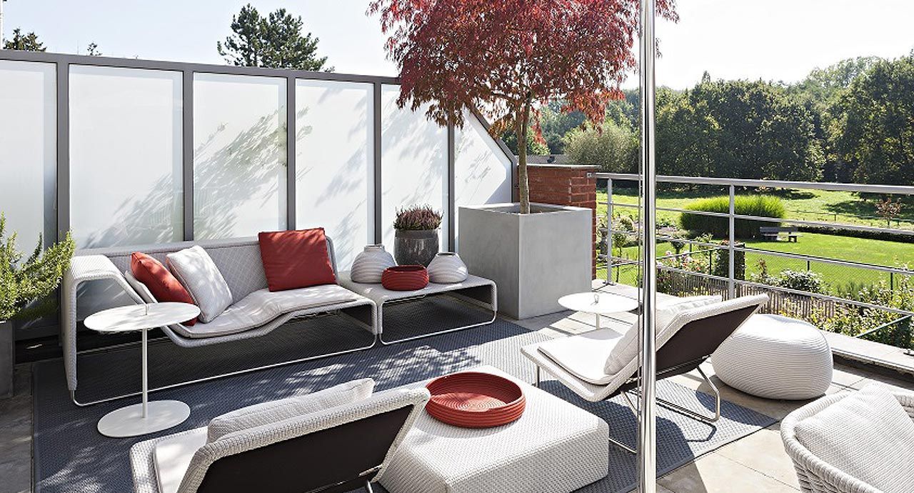 Een terras met een bank, stoelen en een boom
