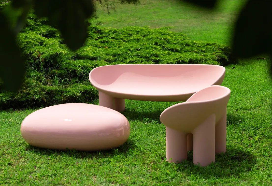Een roze tafel en stoelen staan ​​op een weelderig groen veld.