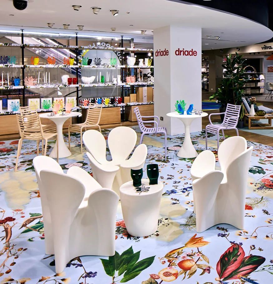 Witte stoelen en tafels in een kamer met een bord waarop driedo staat
