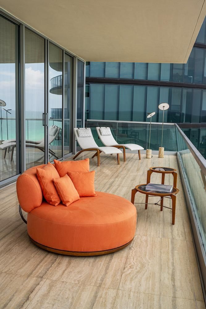 Een groot balkon met een ronde oranje stoel en stoelen.