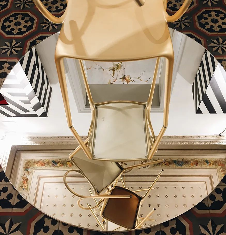 Een gouden stoel staat op een ronde spiegel