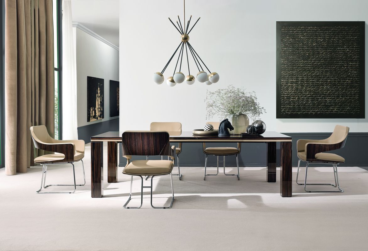 Een eetkamer met een tafel, stoelen en een kroonluchter aan het plafond.