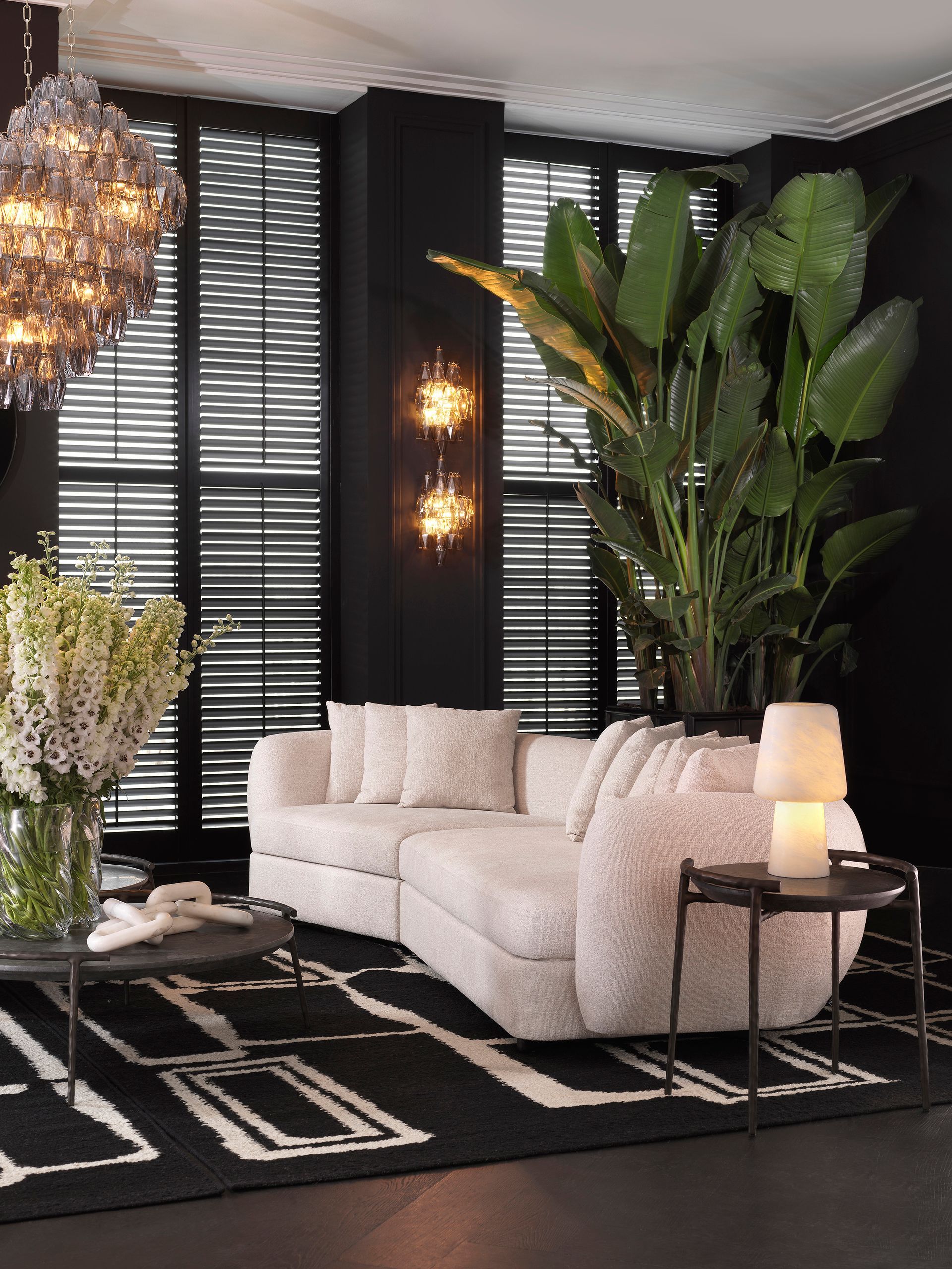 Een woonkamer met een witte hoekbank en een zwart-wit vloerkleed