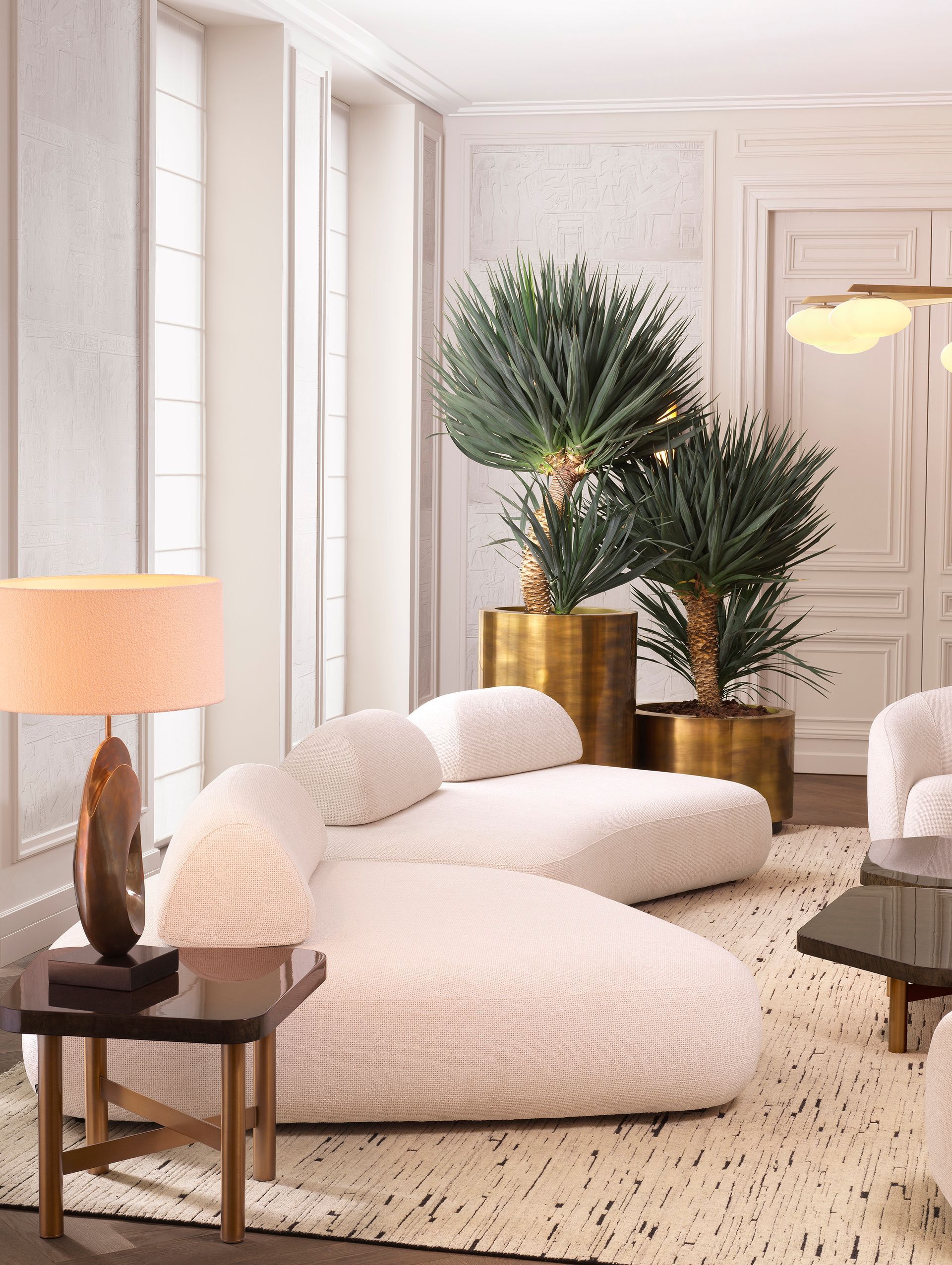 Een woonkamer met een bank, stoelen, lampen en planten.