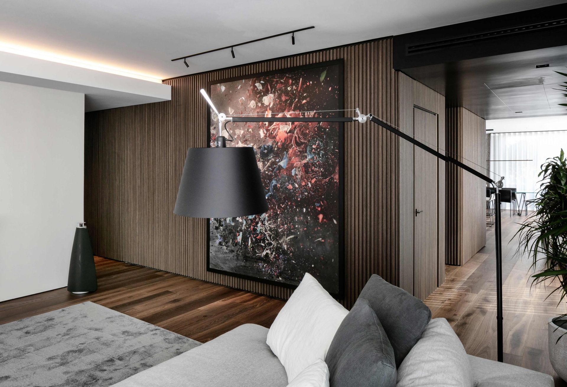 Een woonkamer met een bank, een lamp en een groot schilderij aan de muur