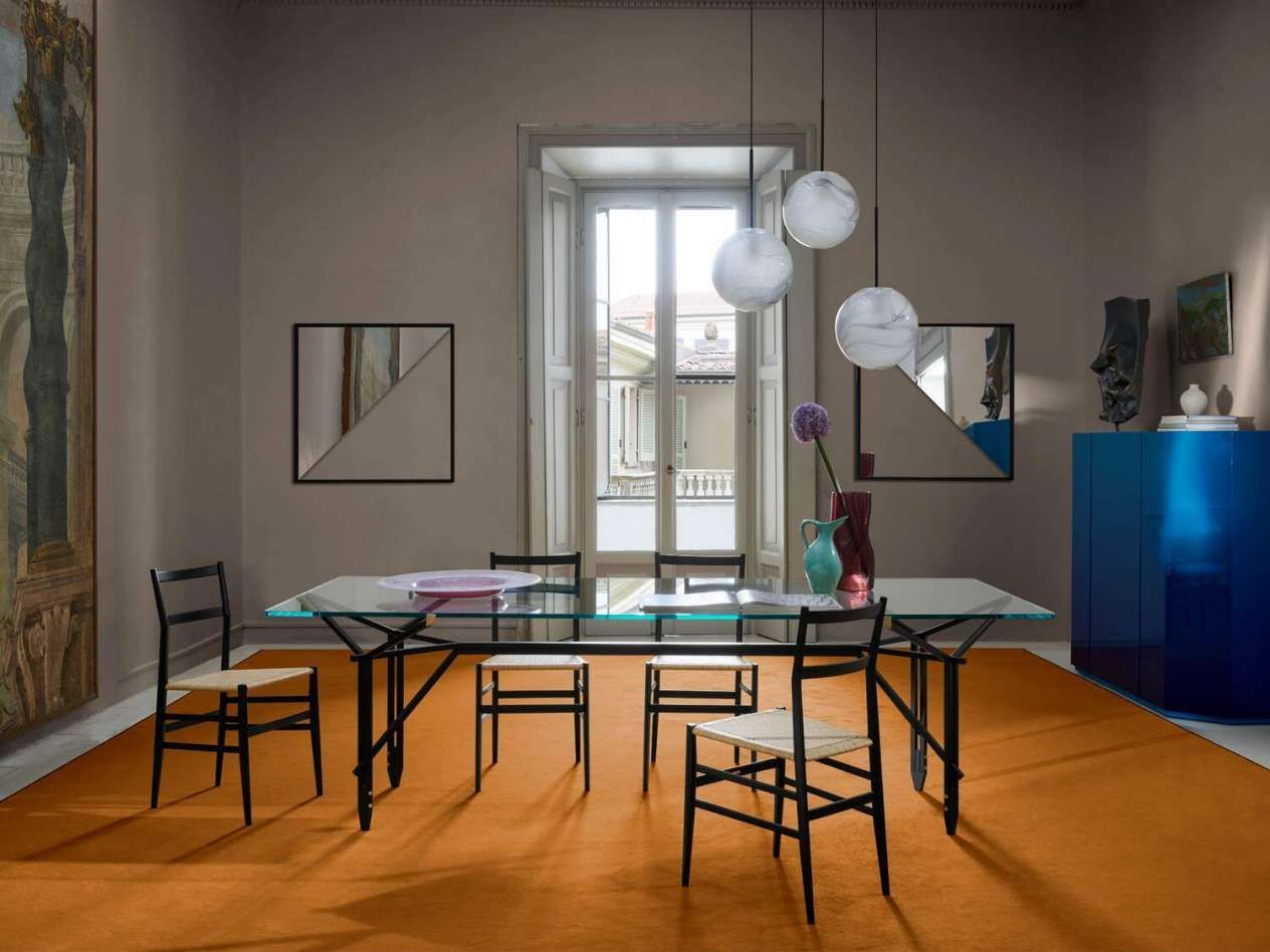 Een eetkamer met een glazen tafel en stoelen