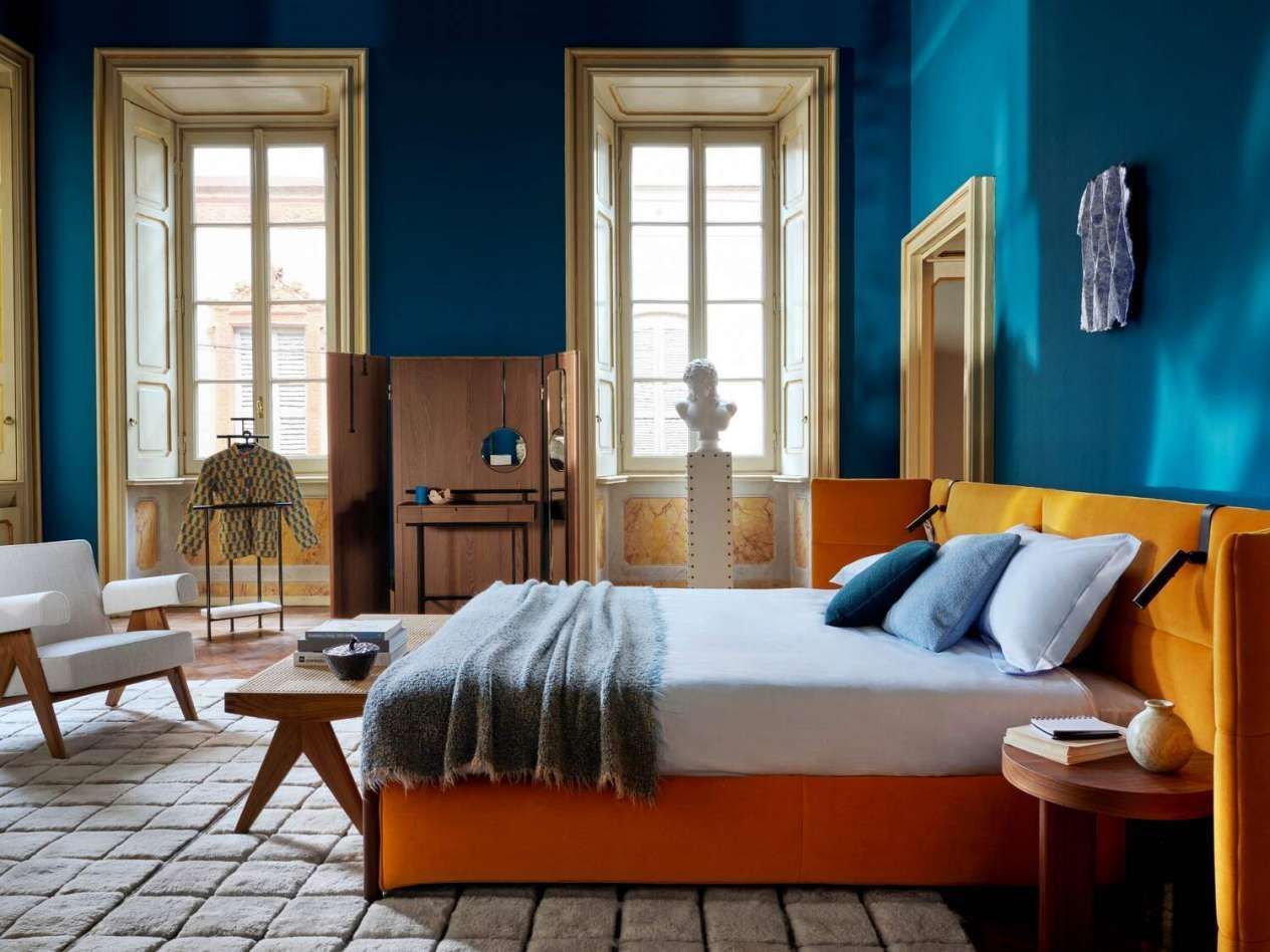 Een slaapkamer met blauwe muren en een oranje bed