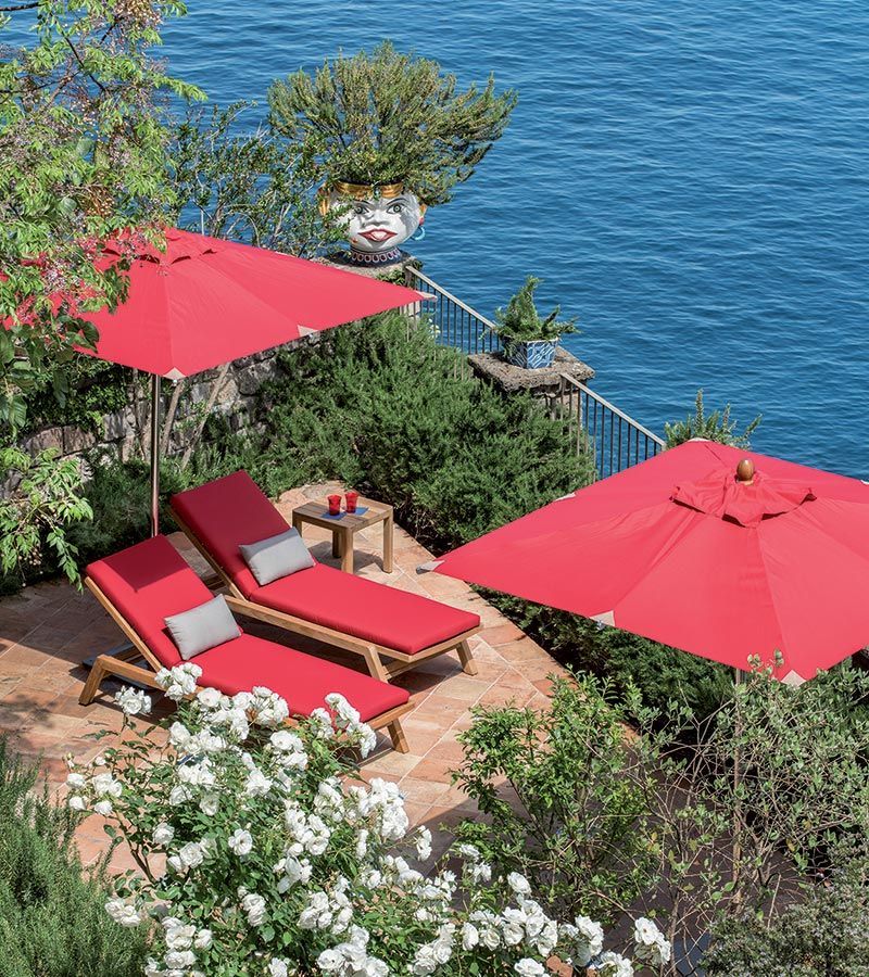 Een terras met rode stoelen en rode parasols met uitzicht op de oceaan.