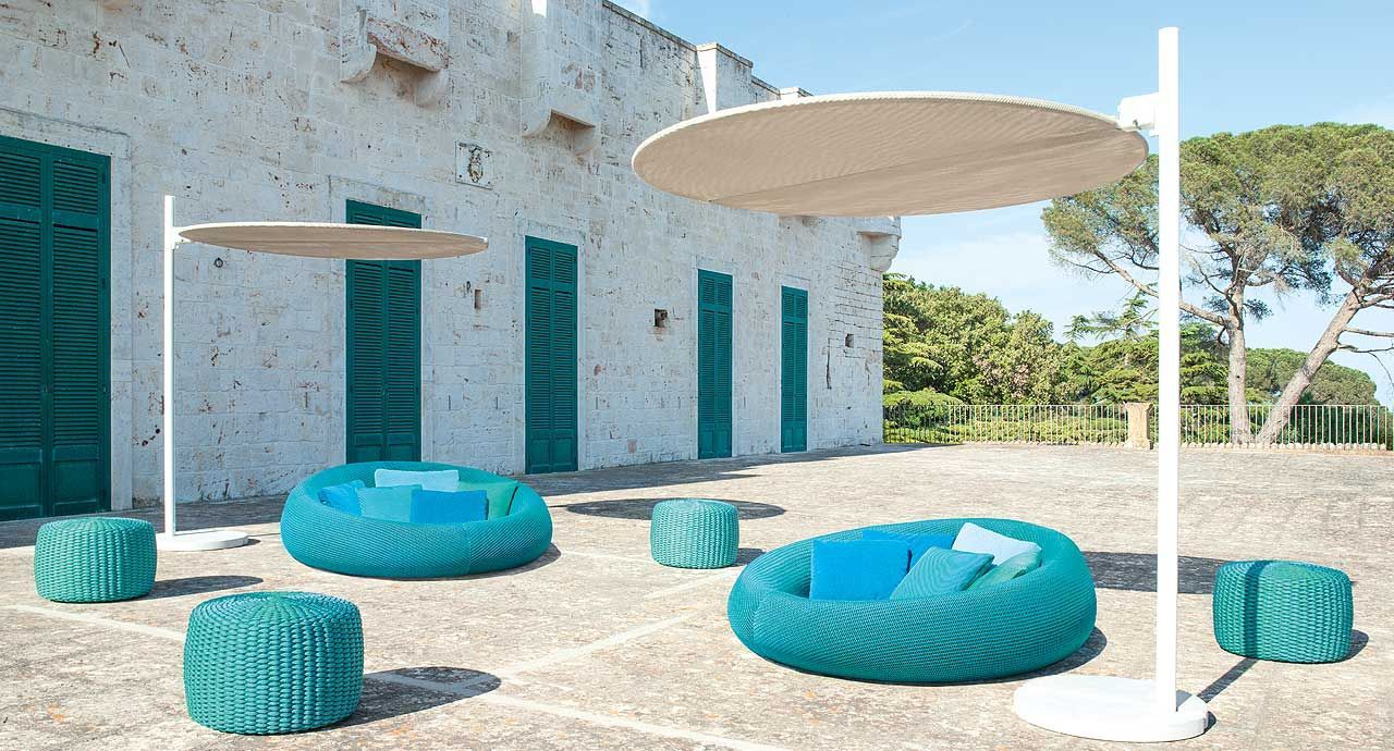 Een terras met blauwe meubels en parasols voor een wit gebouw.
