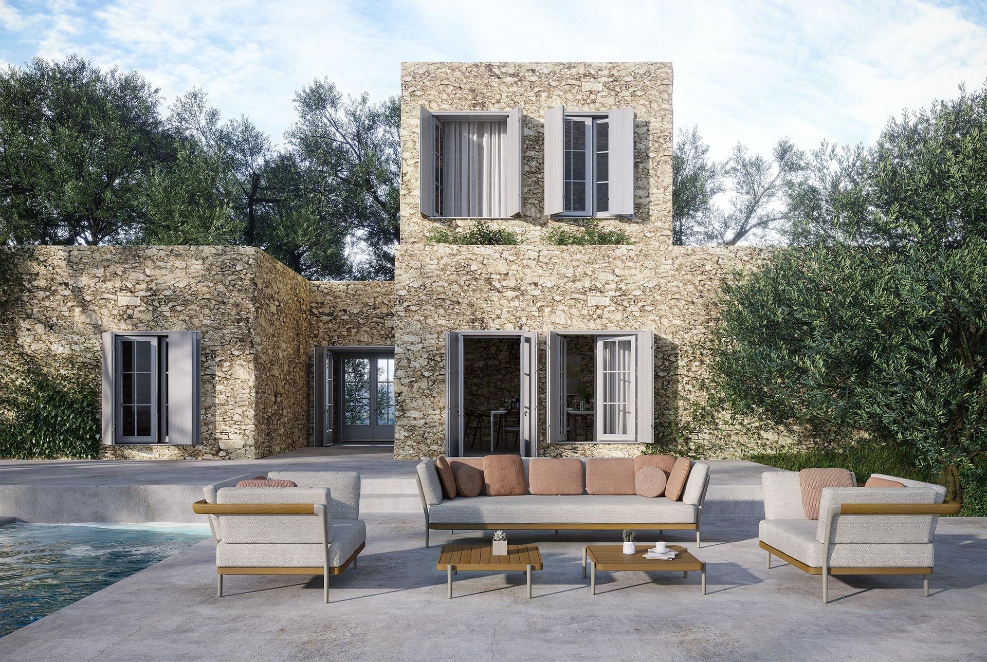 Een stenen huis met een terras met een bank en stoelen ervoor