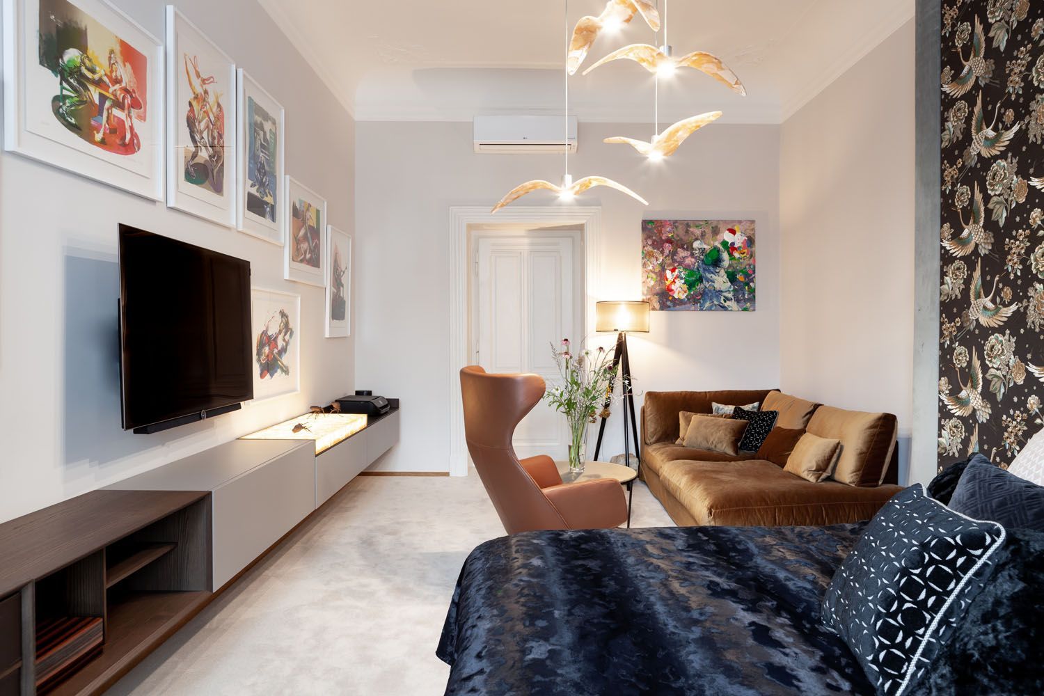 Een woonkamer met een bank, stoel, televisie en een bed.