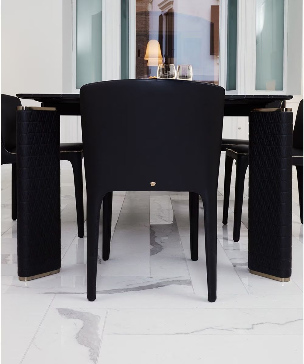 Een eettafel met zwarte stoelen en een glazen blad