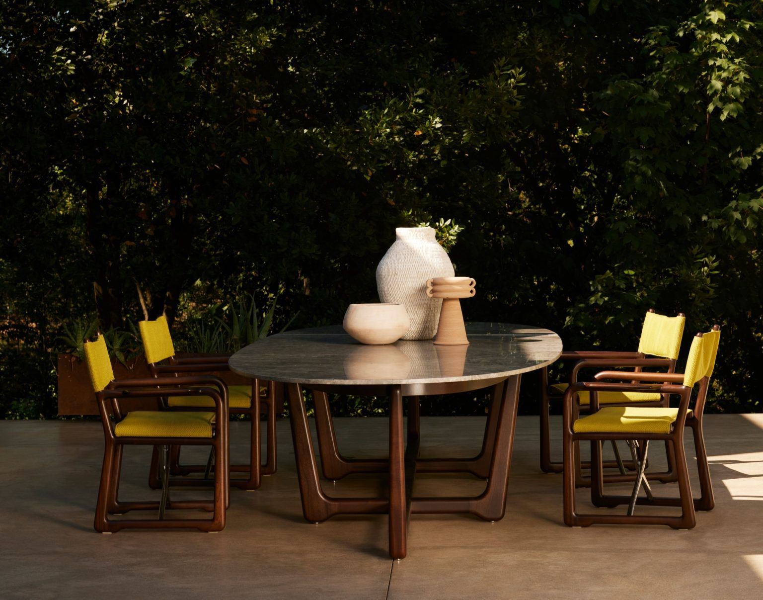Een tafel met gele stoelen en een vaas erop