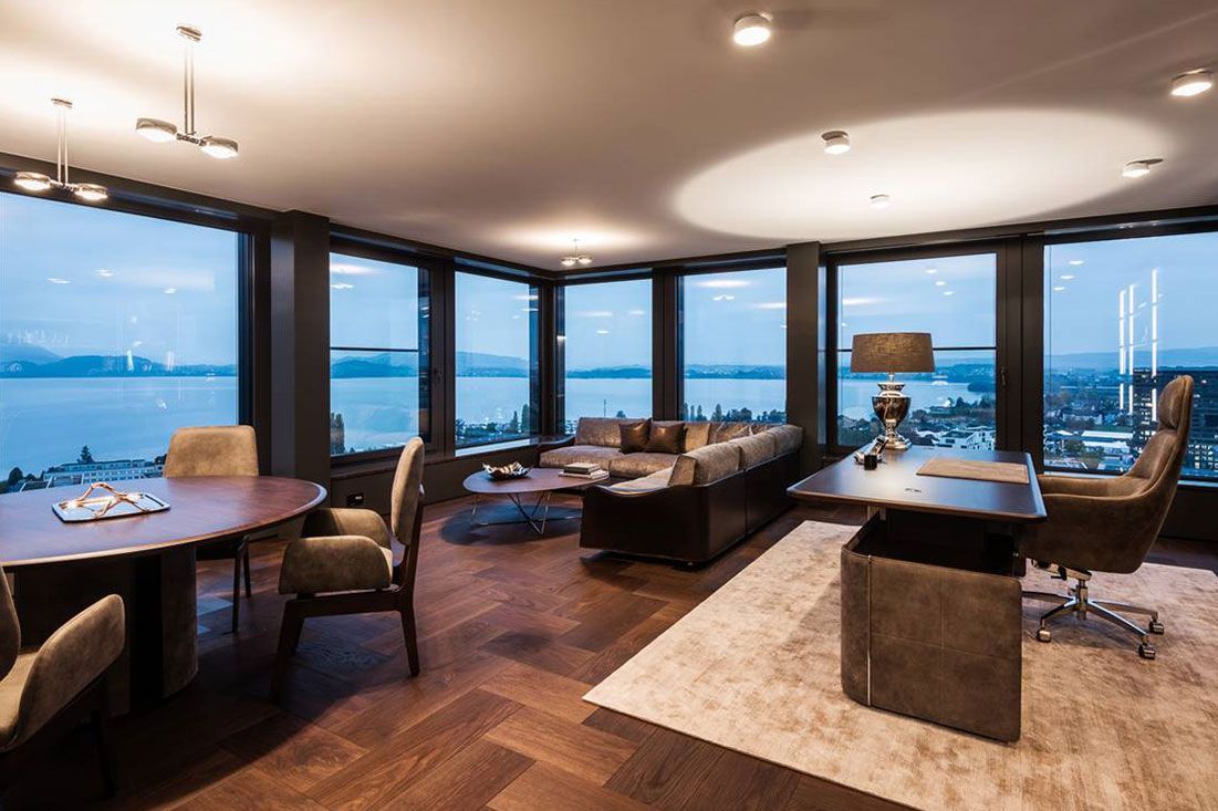 Een woonkamer met veel ramen en uitzicht op een meer.