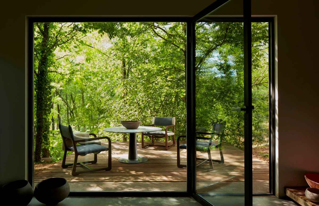 Een kamer met een glazen schuifdeur die leidt naar een terras met een tafel en stoelen.