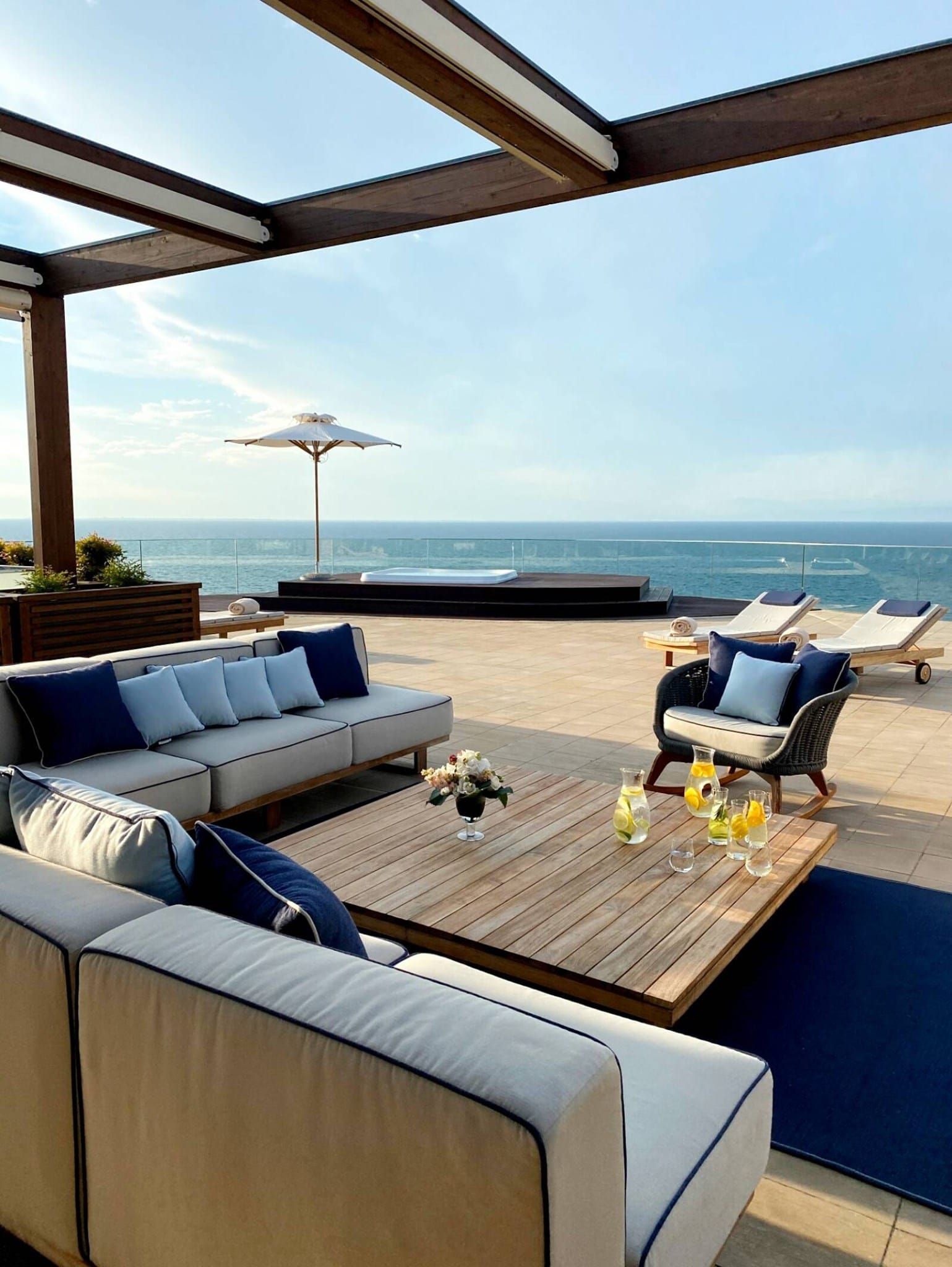 Een terras met een bank, stoelen en een tafel met uitzicht op de oceaan.