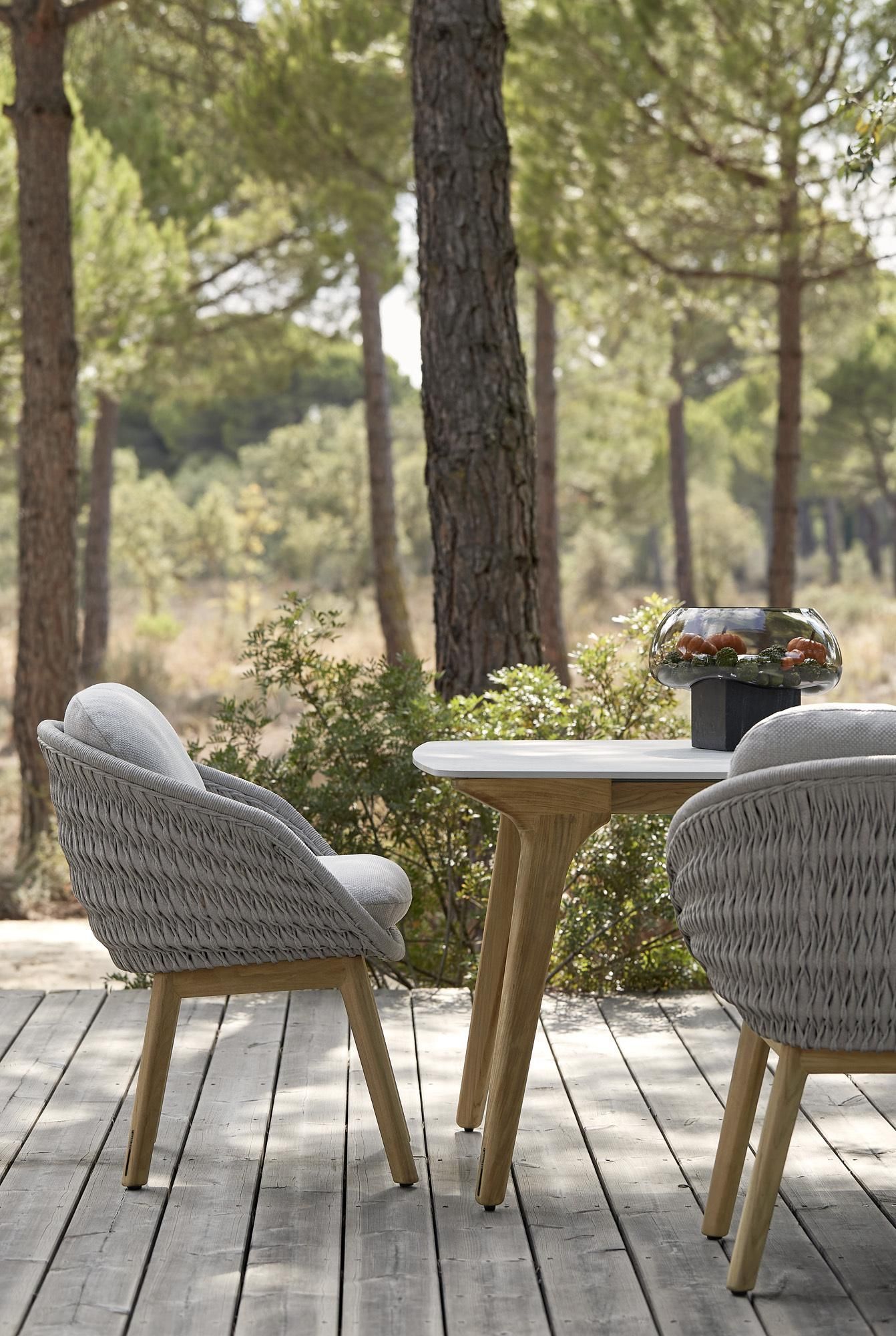 Een tafel en stoelen staan ​​op een houten terras in het bos.