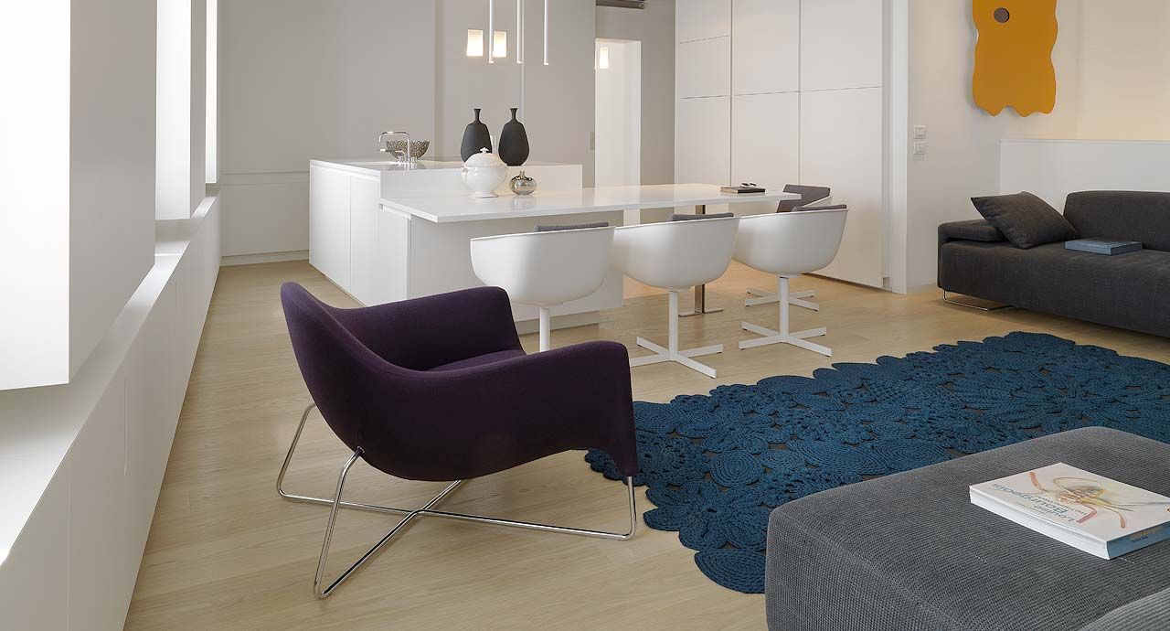 Een woonkamer met een paarse stoel en een blauw kleed