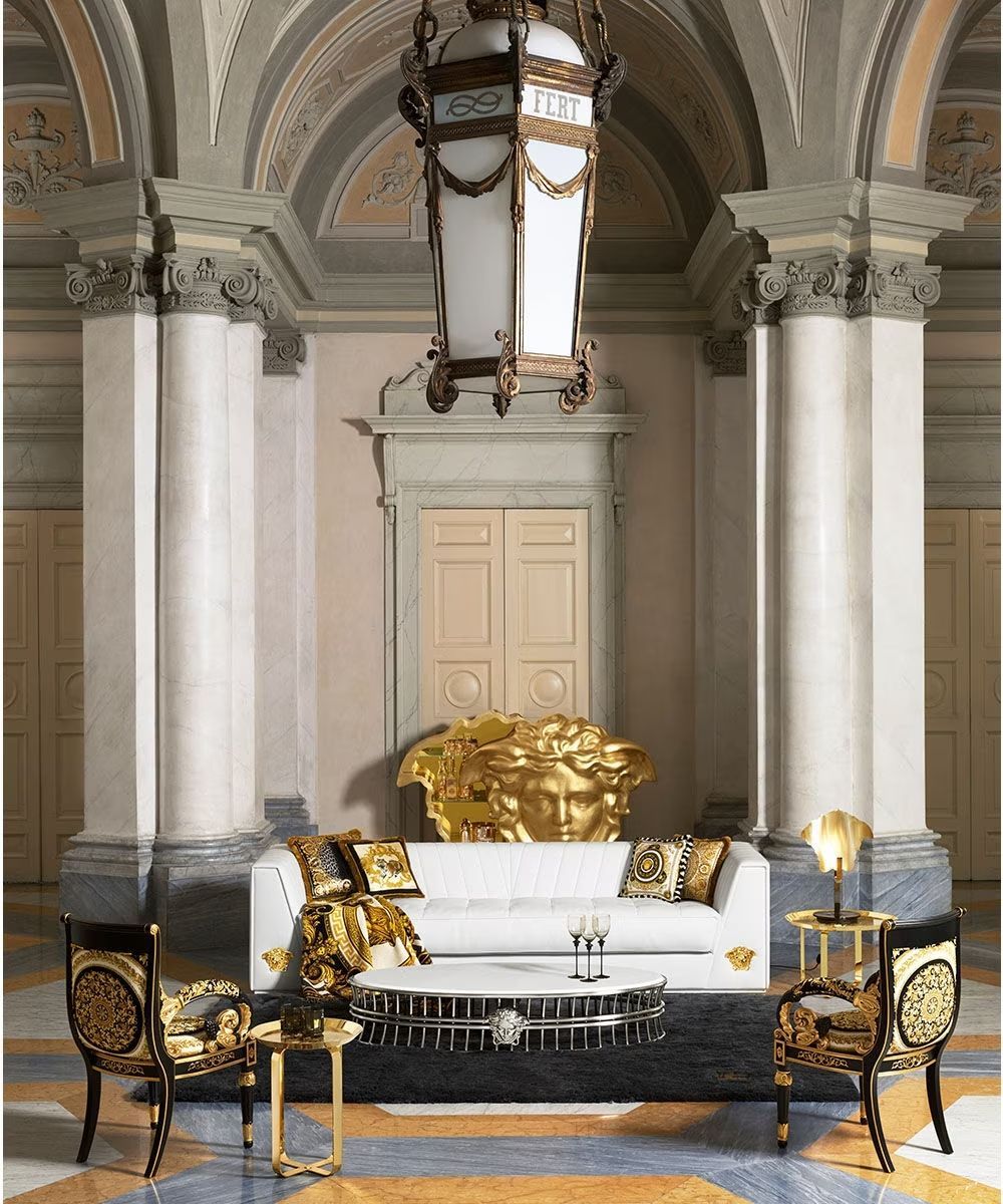Een woonkamer met een bank, stoelen, tafels en een kroonluchter die aan het plafond hangt.
