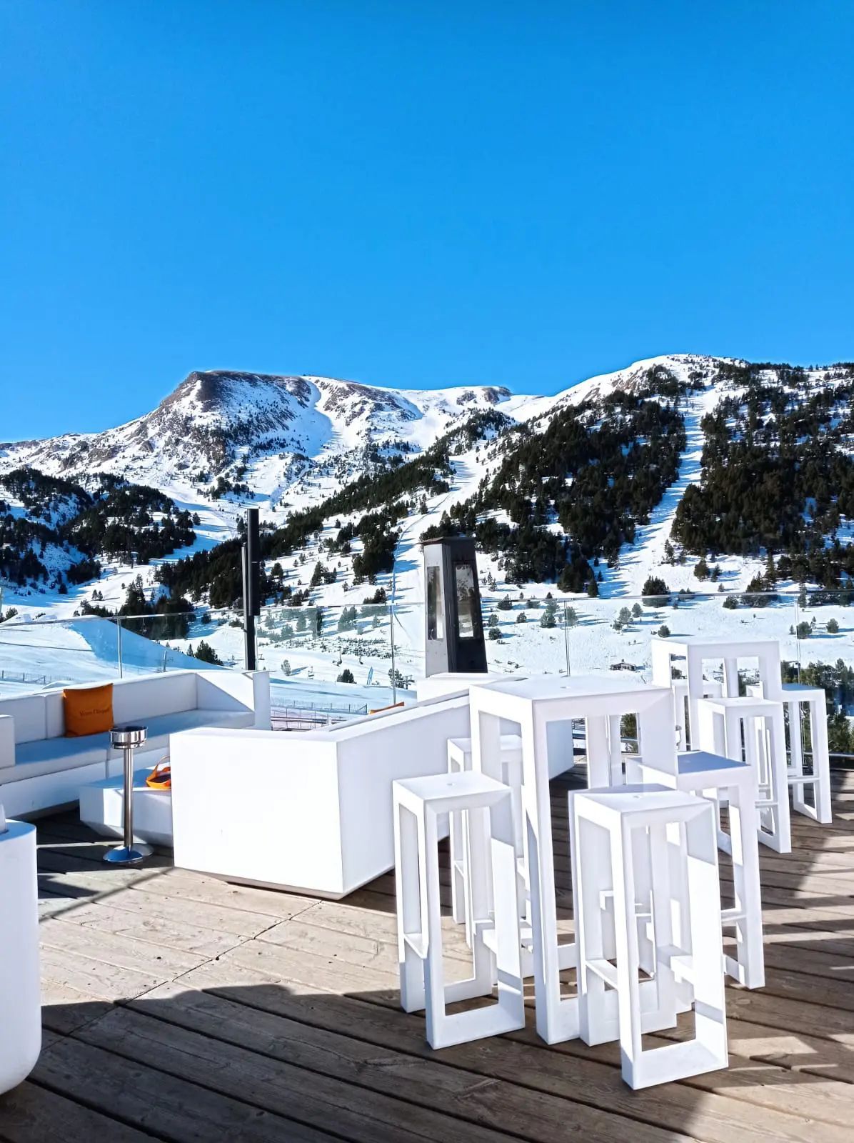 Een terras met tafels en stoelen met bergen op de achtergrond
