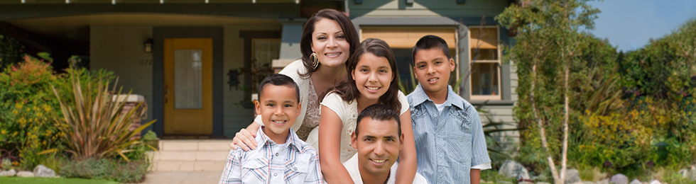 A family is posing for a picture in front of their house. A family is posing for a picture in front of their house.