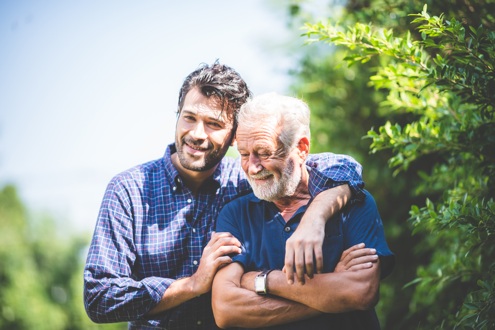 A young man is hugging an older man in a park. A young man is hugging an older man in a park.