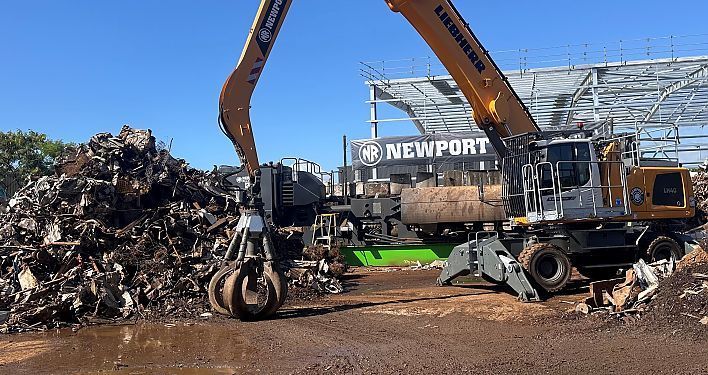 A Liebherr material handler loading scrap metal at a recycling center with