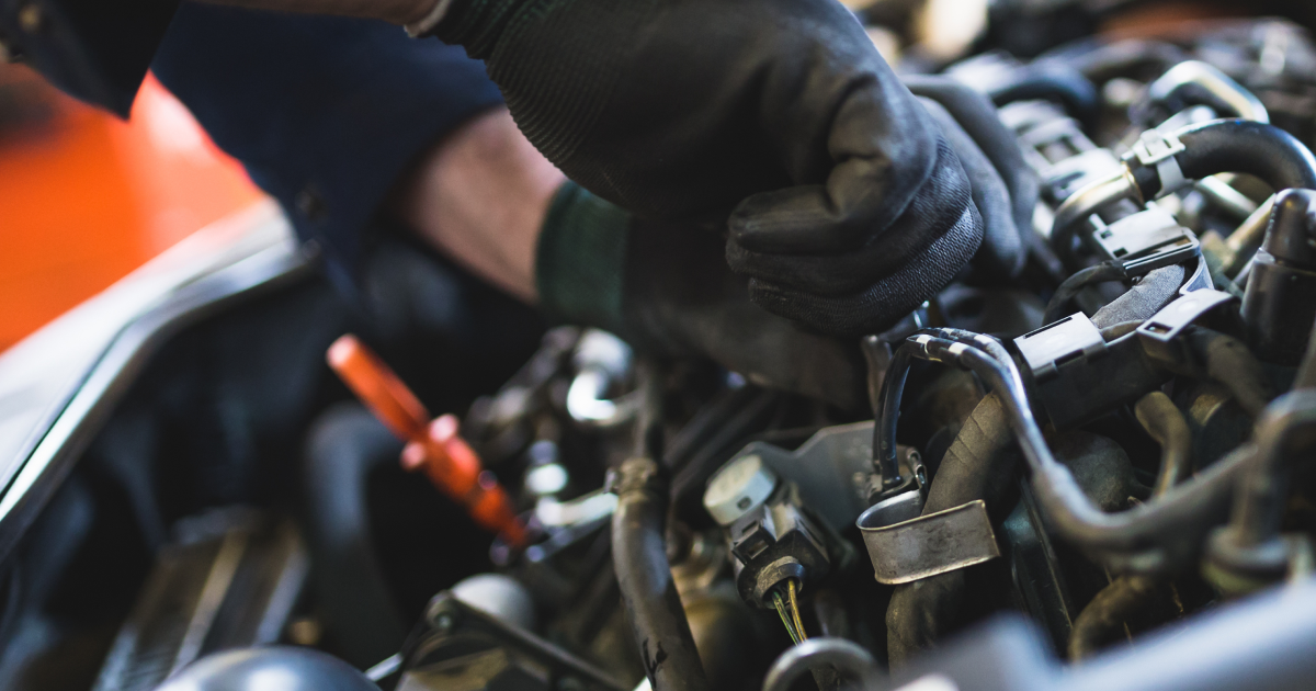 Mechanic wearing black gloves repairing an engine in a car workshop | Madison Automotive