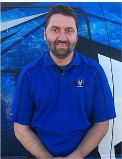 Man in blue polo shirt seated against a blue abstract background, smiling at the camera | Madison Automotive