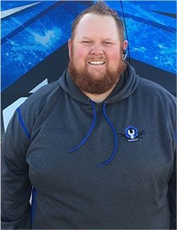 Smiling man in a dark gray hoodie standing before a blue backdrop | Madison Automotive