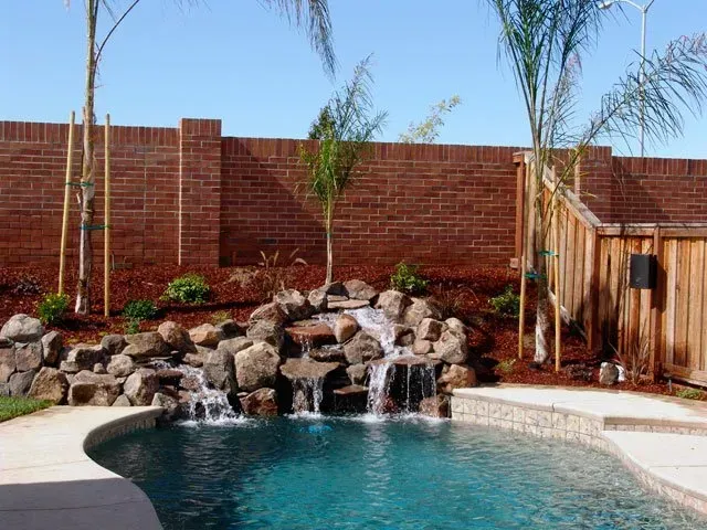 A swimming pool with a waterfall in the backyard