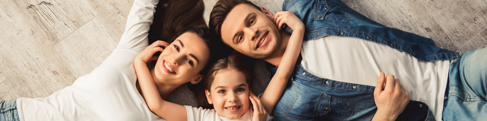 Three people lying on a bed, smiling and resting their heads together.