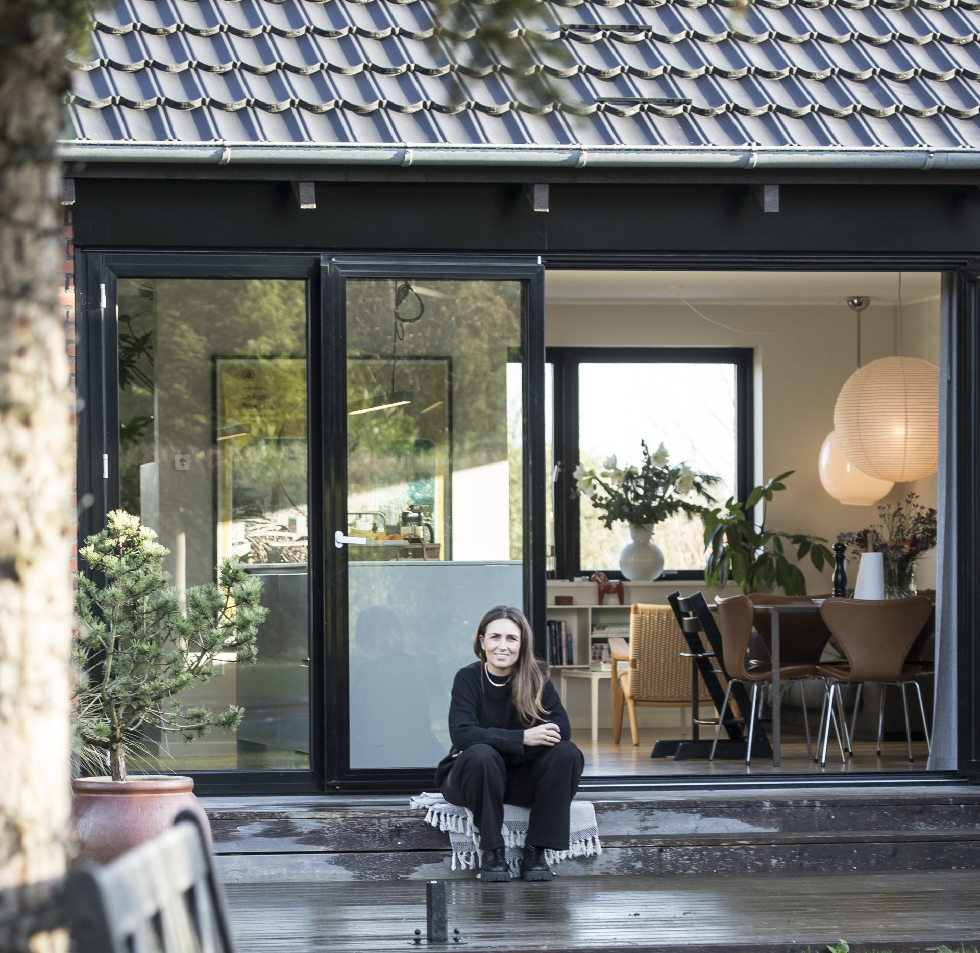 Kvinde på terrasse foran hus