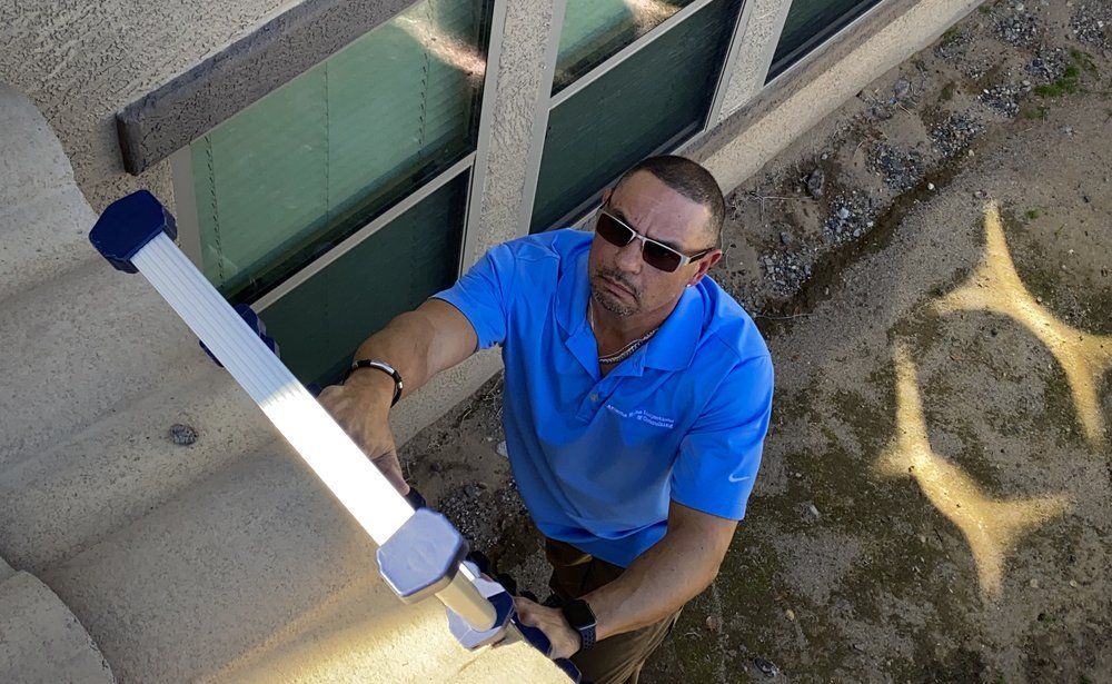 A man in a blue shirt is holding a flashlight in front of a building.