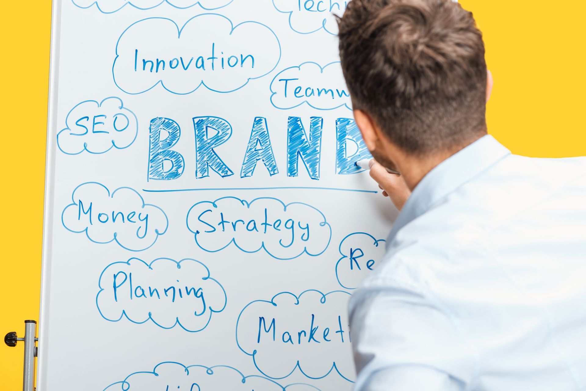 A man is writing the word brand on a whiteboard