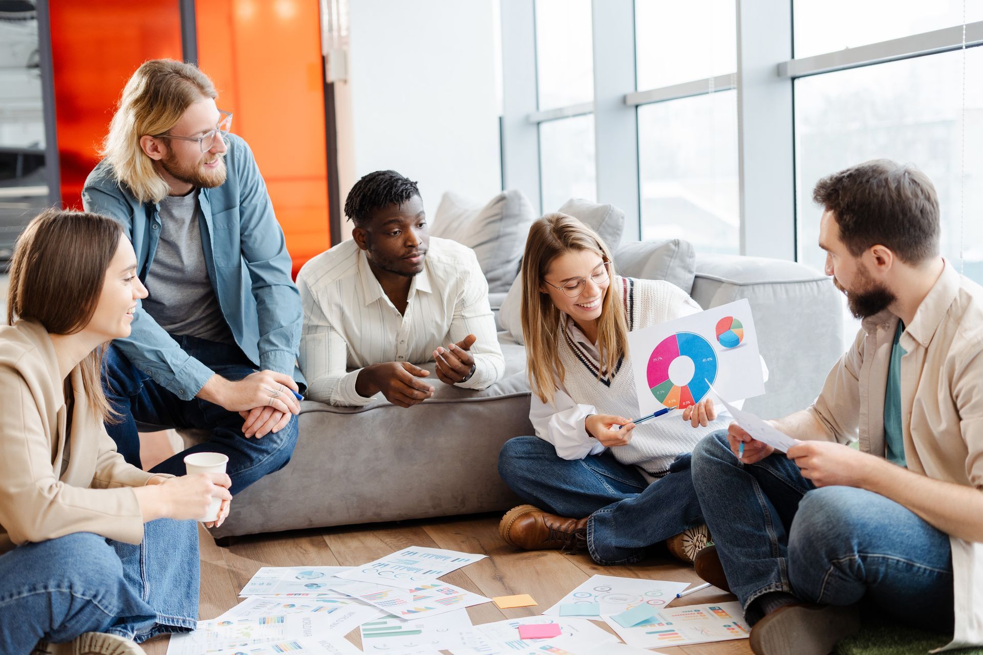 A group of people are sitting on the floor having a meeting.